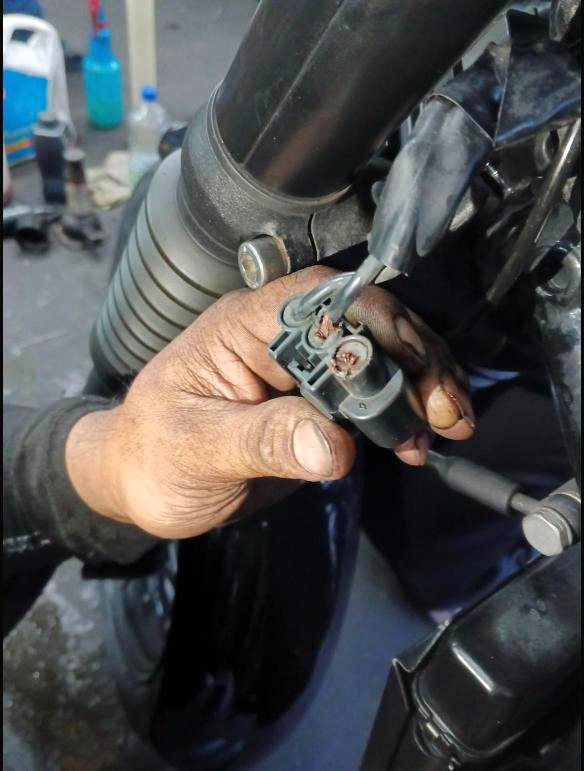 Boy Motorbike mechanic repairing a corroded wiring connector on a big bike